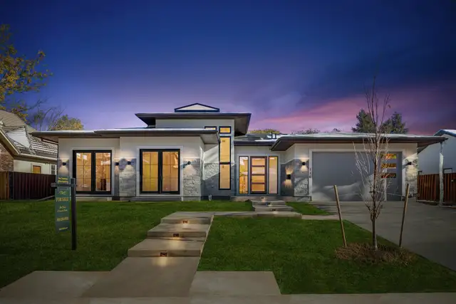 Modern two-storey home at dusk with lights on inside