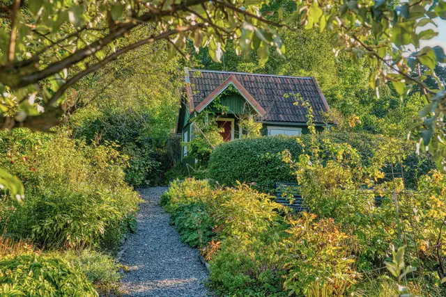Small cottage with a tiled roof behind a green garden and gravel path