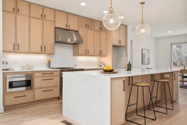 Kitchen with wood cabinets, a white island and pendant lights