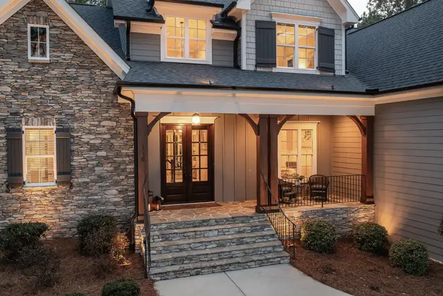 Stone house with a lit front porch and steps at dusk