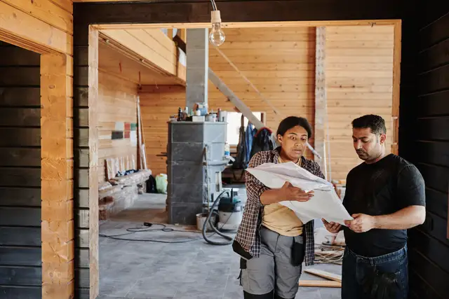 Builder and client reading plans together inside a timber house under construction